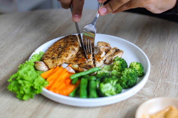 How to lose body fat through diet with a balanced meal of grilled chicken, broccoli, carrots and other nutrient-rich foods.