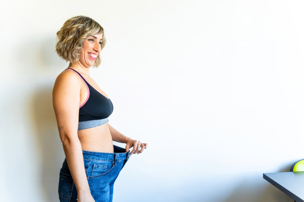 How to lose weight and keep it off, represented by a woman demonstrating weight loss with loose-fitting jeans.